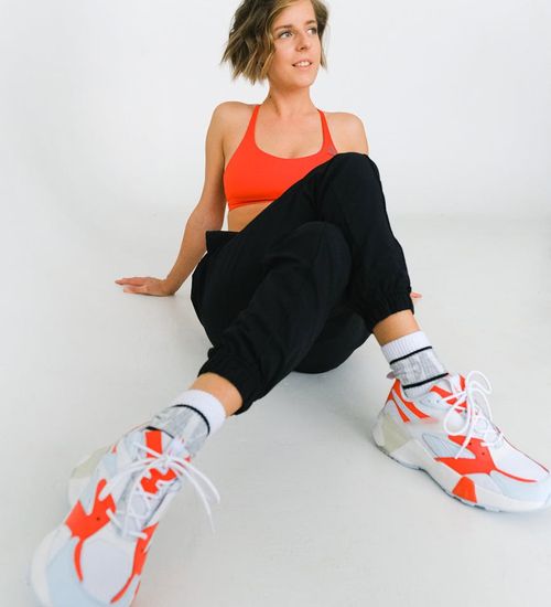 Woman in comfortable sportswear performing a light dynamic exercise in a bright studio.